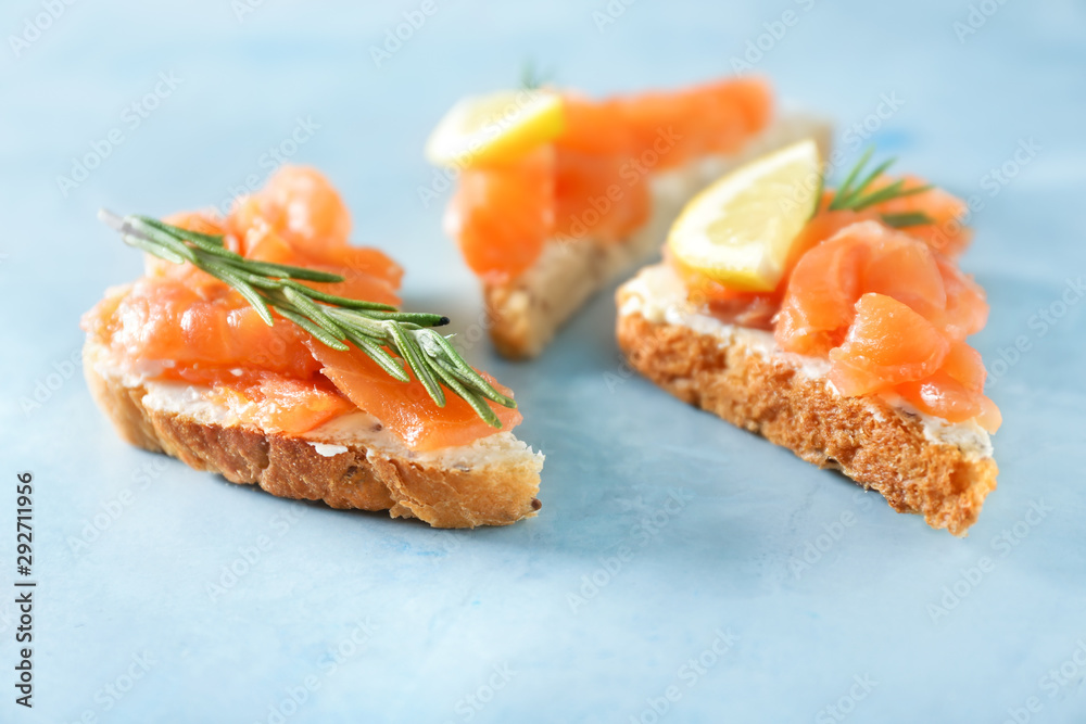 Tasty sandwiches with salmon on color background