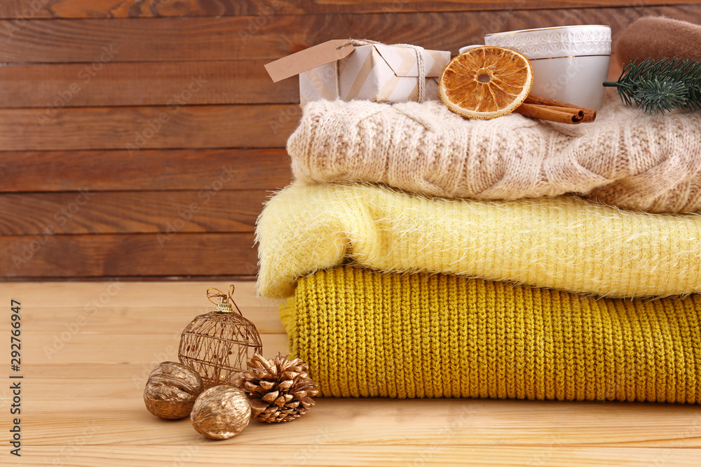 Stack of warm clothes and Christmas gifts on wooden background