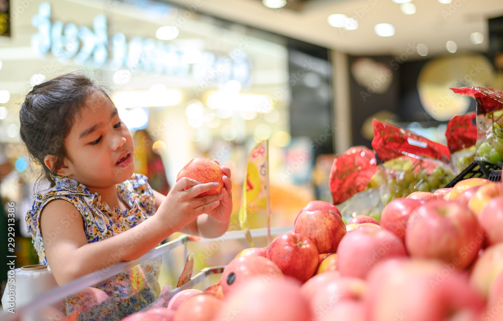 亚洲小女孩在食品店或超市选苹果