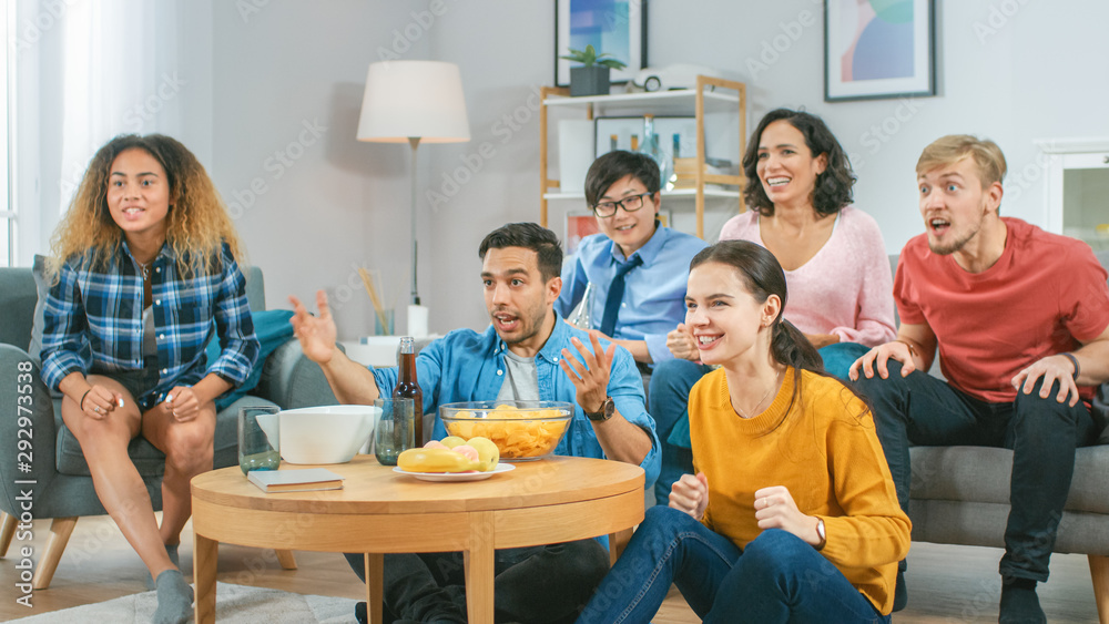 At Home Diverse Group Friends Watching TV Together, Eating Snacks and Drinking Beverage. They Probab