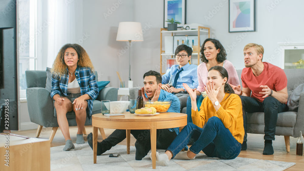 At Home Diverse Group Friends Watching TV Together, Eating Snacks and Drinking Beverage. They Probab