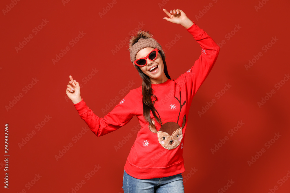 Young woman in Christmas sweater and knitted hat on color background