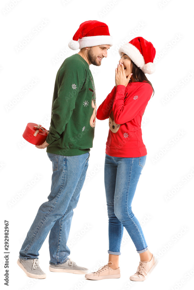 Man hiding Christmas gift for his wife behind back against white background