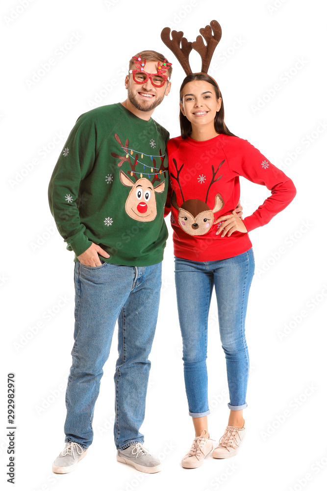 Funny young couple in Christmas sweaters on white background