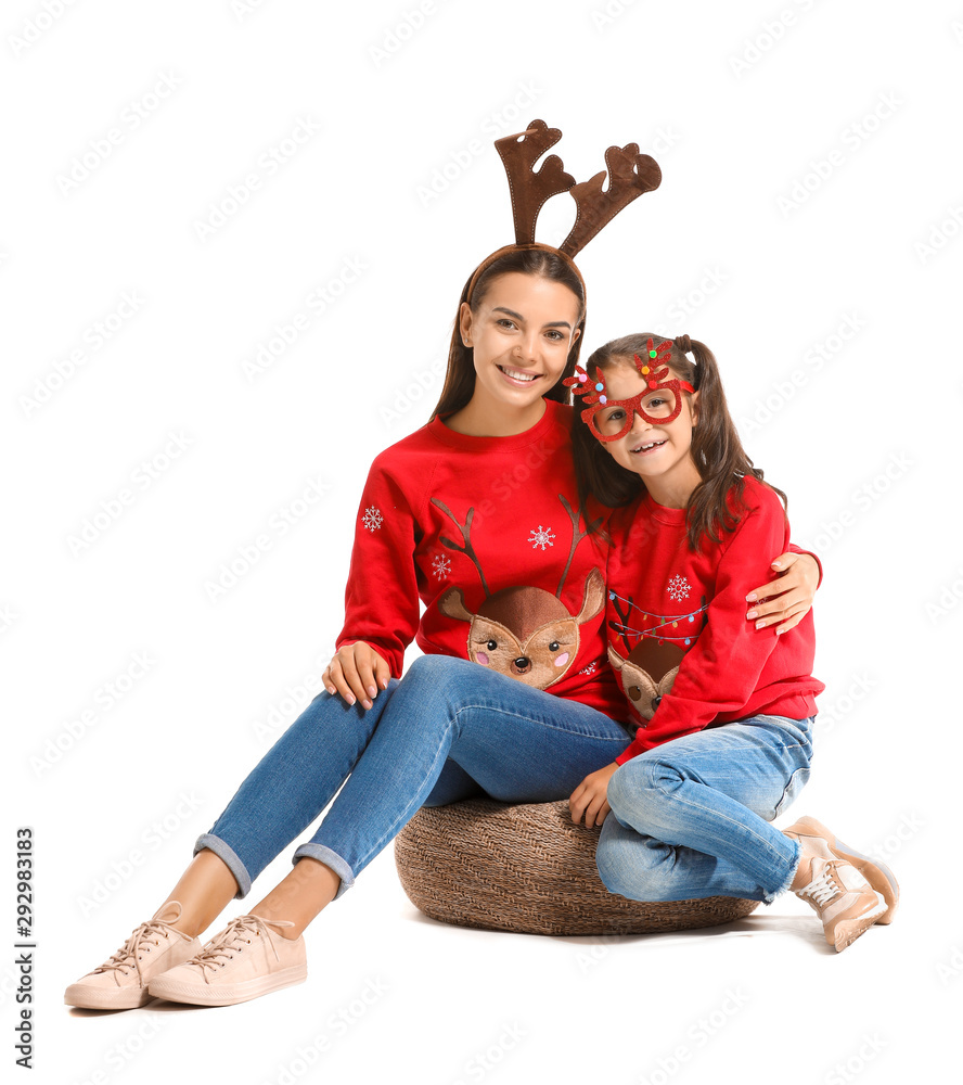 Funny young woman and her daughter in Christmas sweaters on white background