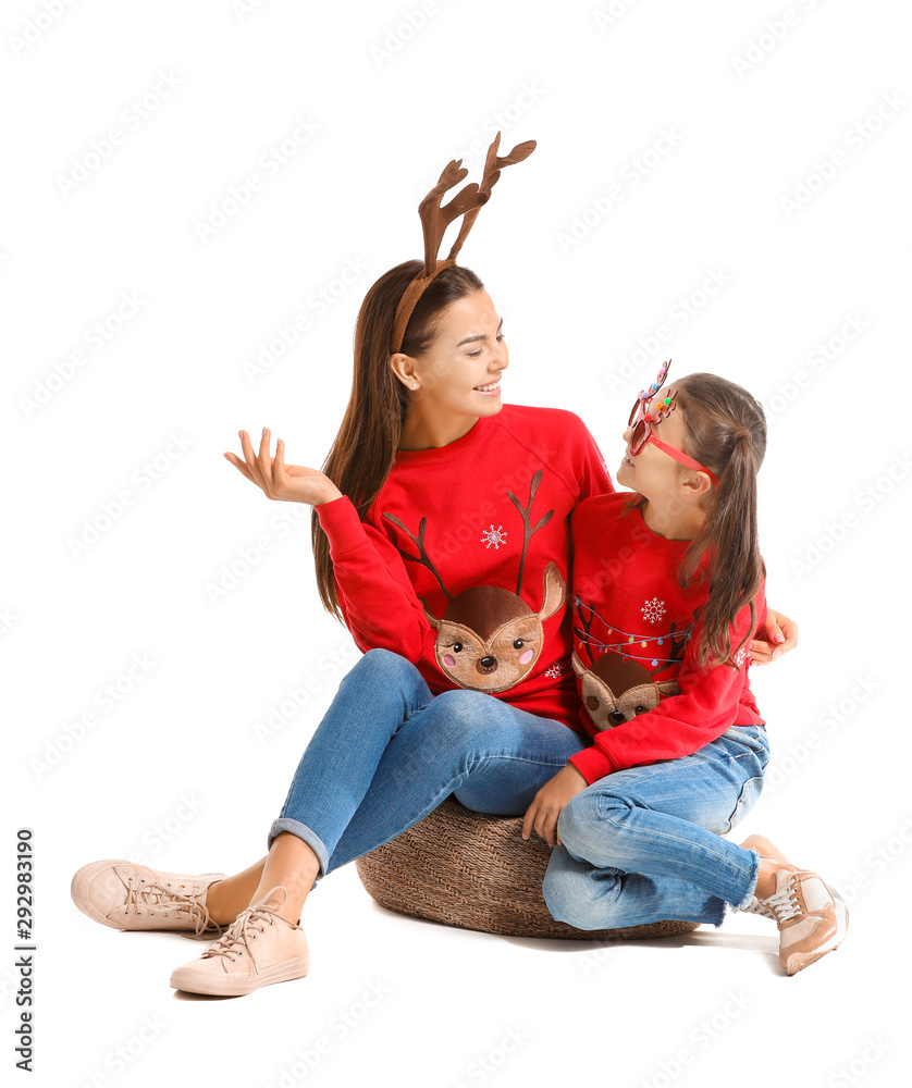 Funny young woman and her daughter in Christmas sweaters on white background