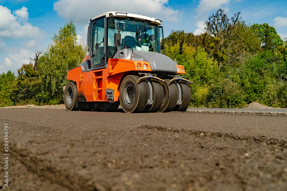 压路机在新的道路施工现场工作。在道路上铺设新的沥青。施工