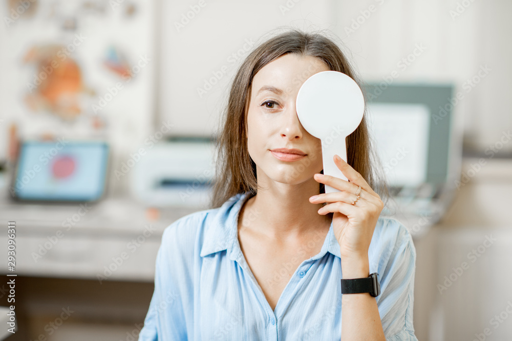 Young woman checking vision covering one eye with an ophthalmic scapula during a medical examination