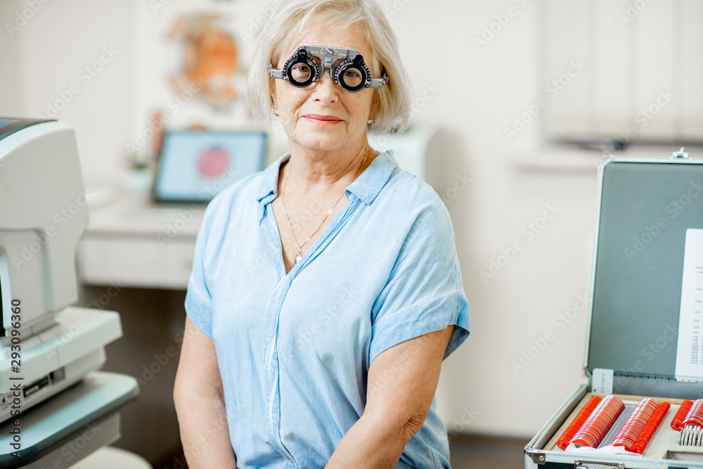 Portrait of a senior woman checking vision with eye test glasses during a medical examination at the