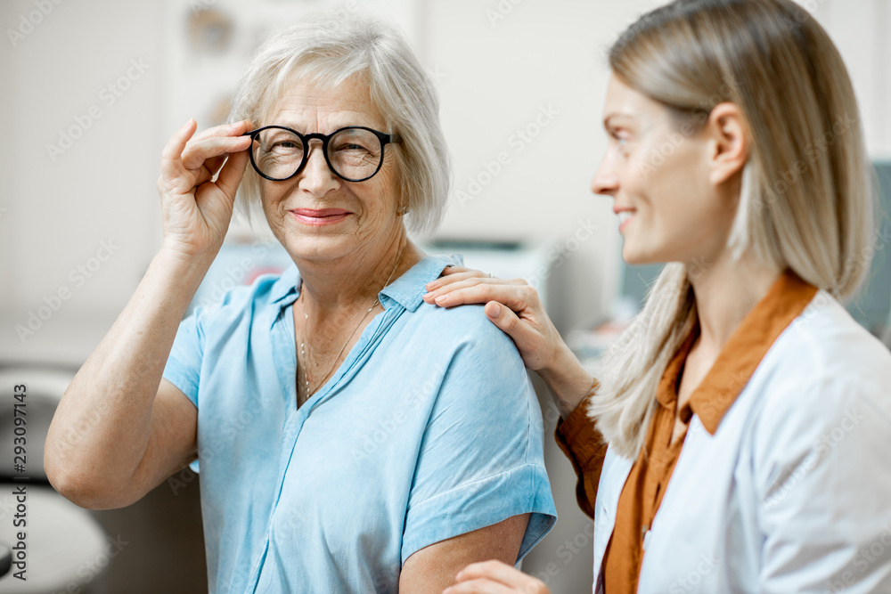 Happy senior woman patient checking vision with new eyeglasses during a medical consultation with op