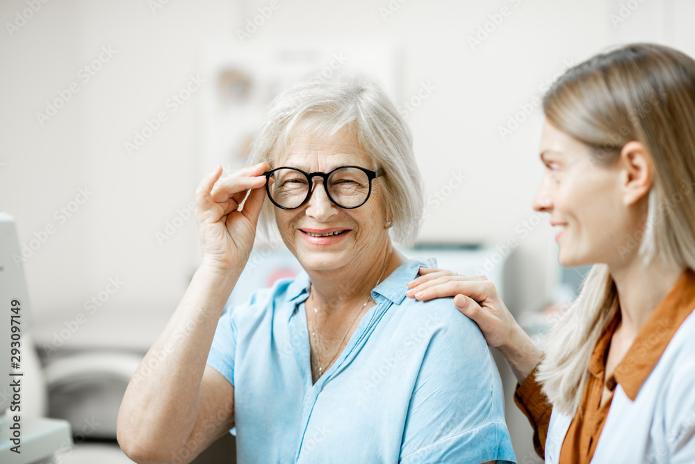 Happy senior woman patient checking vision with new eyeglasses during a medical consultation with op