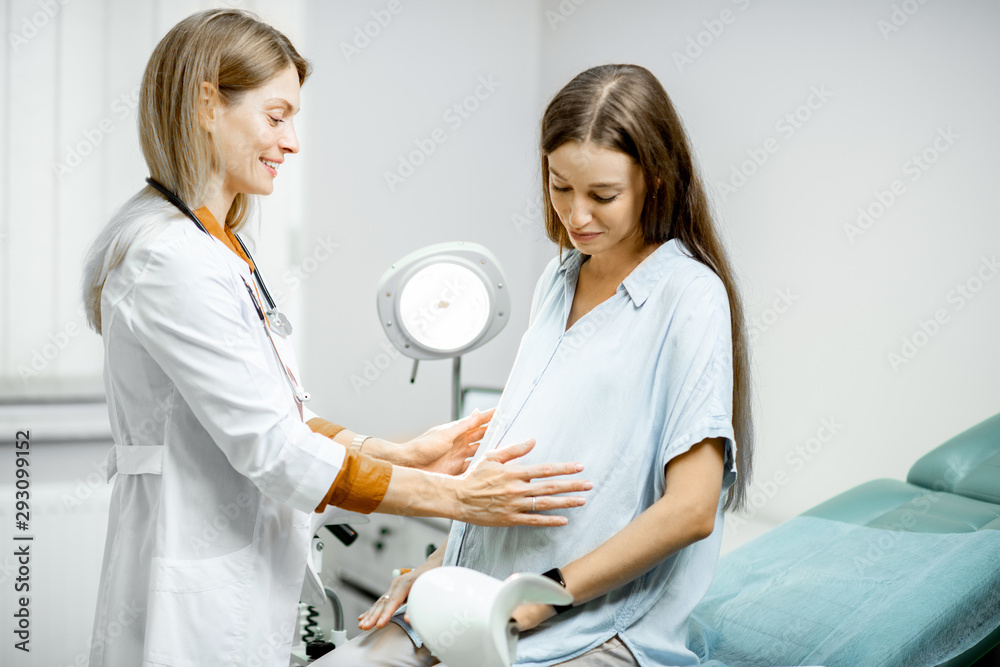 Young pregnant woman sitting on the gynecological chair during a medical consultation with gynecolog