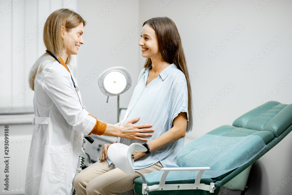 Young pregnant woman sitting on the gynecological chair during a medical consultation with gynecolog