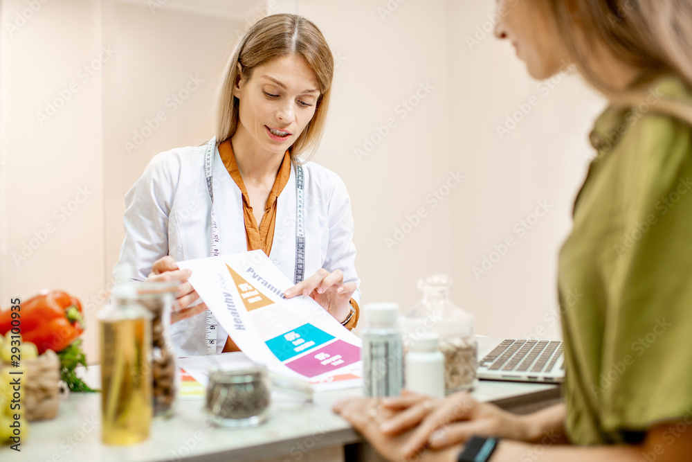 Nutritionist with young woman client talking about meal plan and healthy products during a medical c