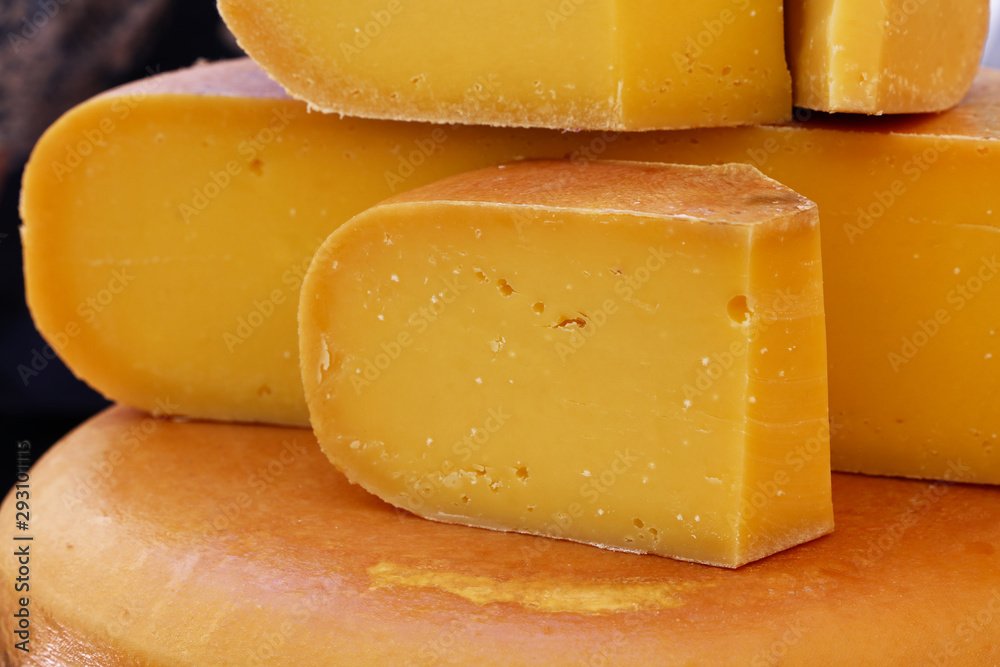 Close up cut slices and wheel of hard gouda cheese