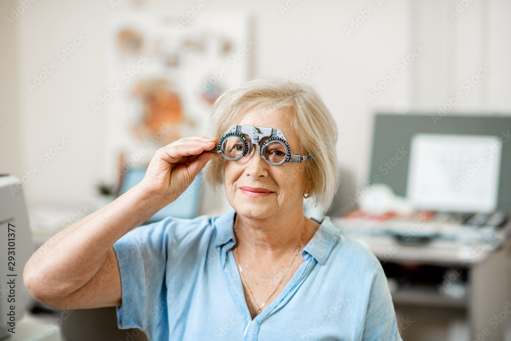 Senior woman checking vision with eye test glasses during a medical examination at the ophthalmologi