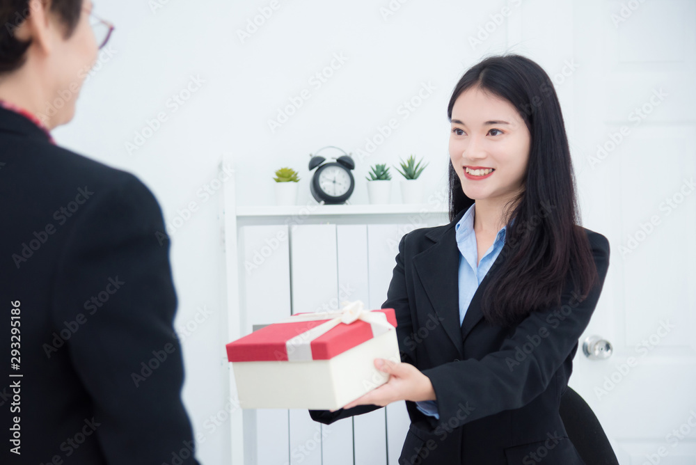 Beautiful young asian businesswoman giving christmas gift to her boss in office