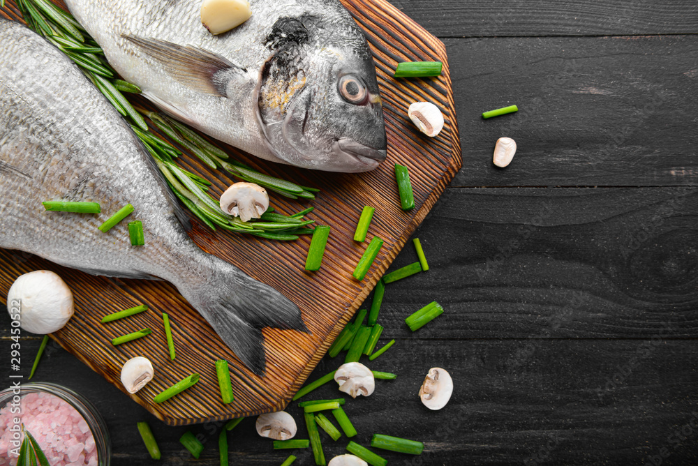 Board with raw dorado fish on dark wooden background