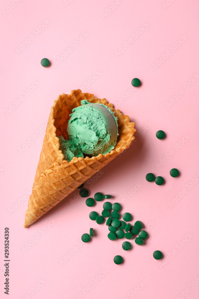 Waffle cone with tasty spirulina ice-cream on color background