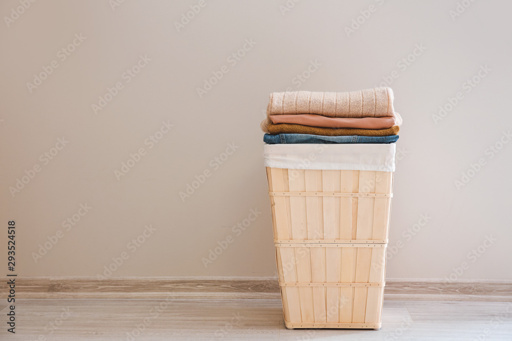 Basket with laundry on floor near light wall