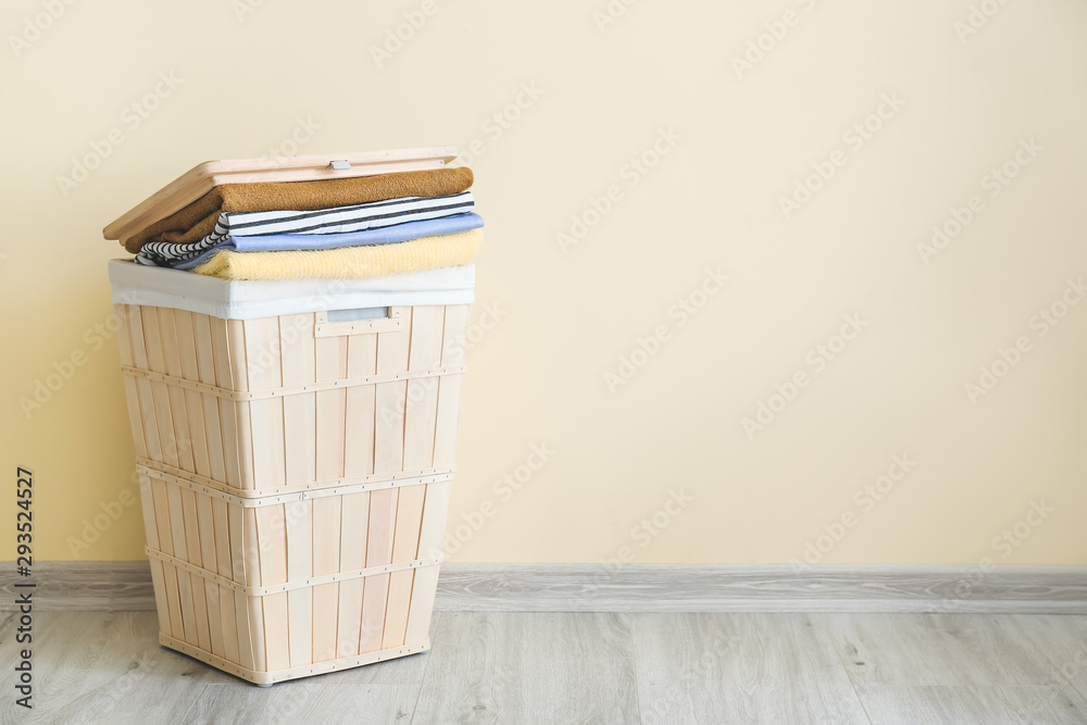 Basket with laundry on floor near light wall