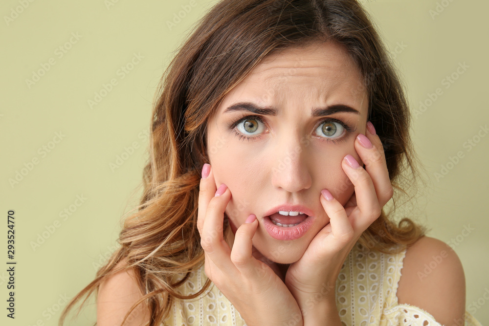 Surprised young woman on color background