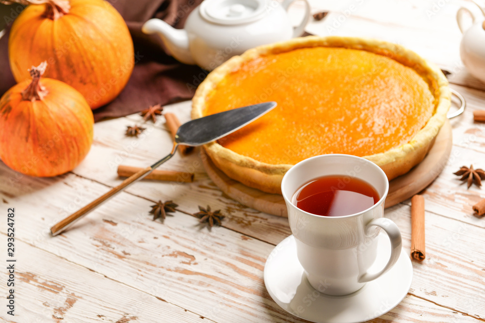 Tasty pumpkin pie and cup of tea on wooden table