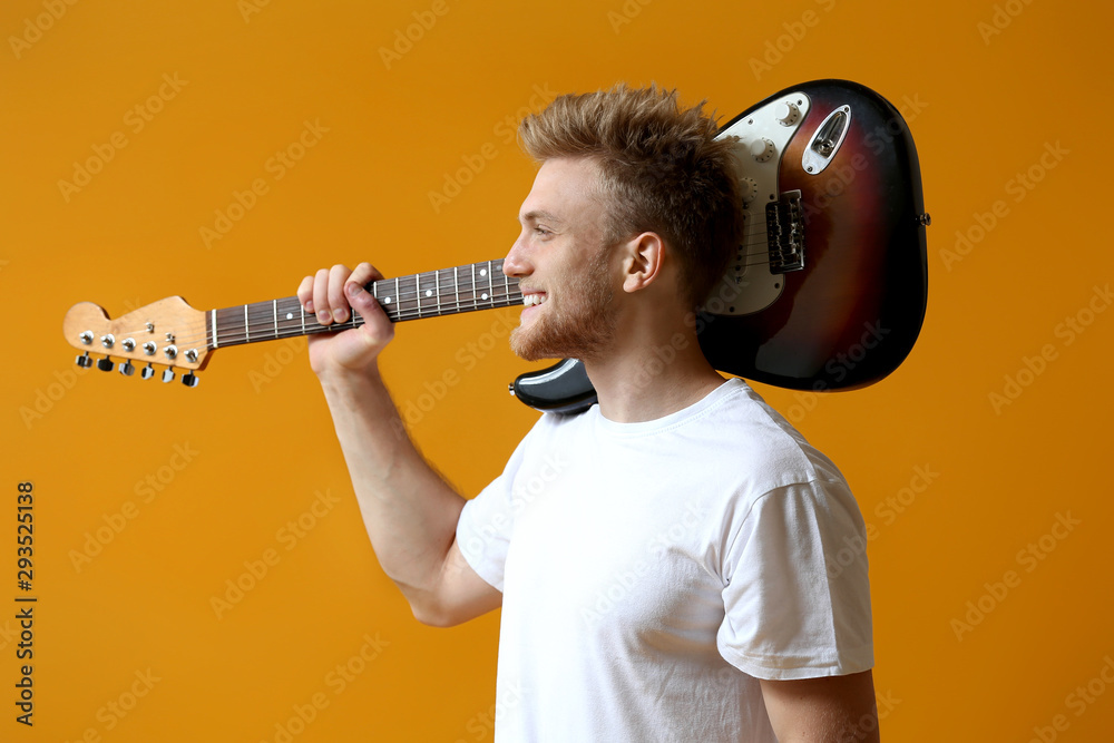 Handsome man with guitar on color background