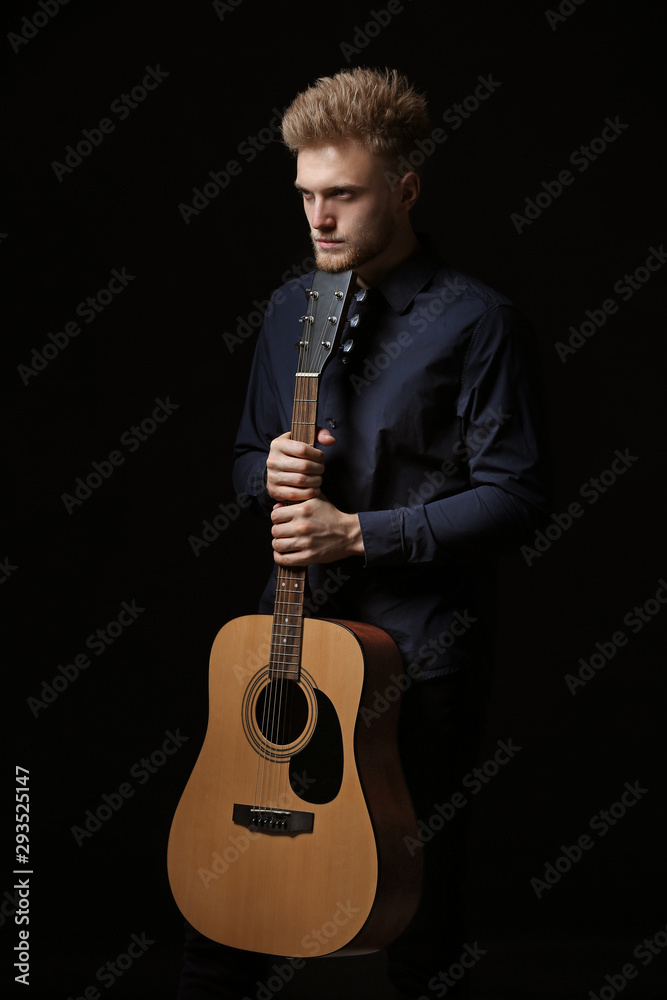 Handsome man with guitar on dark background