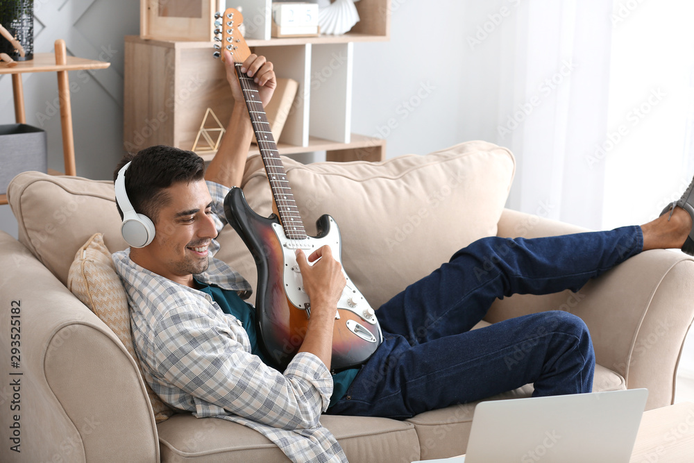 Handsome man playing guitar at home