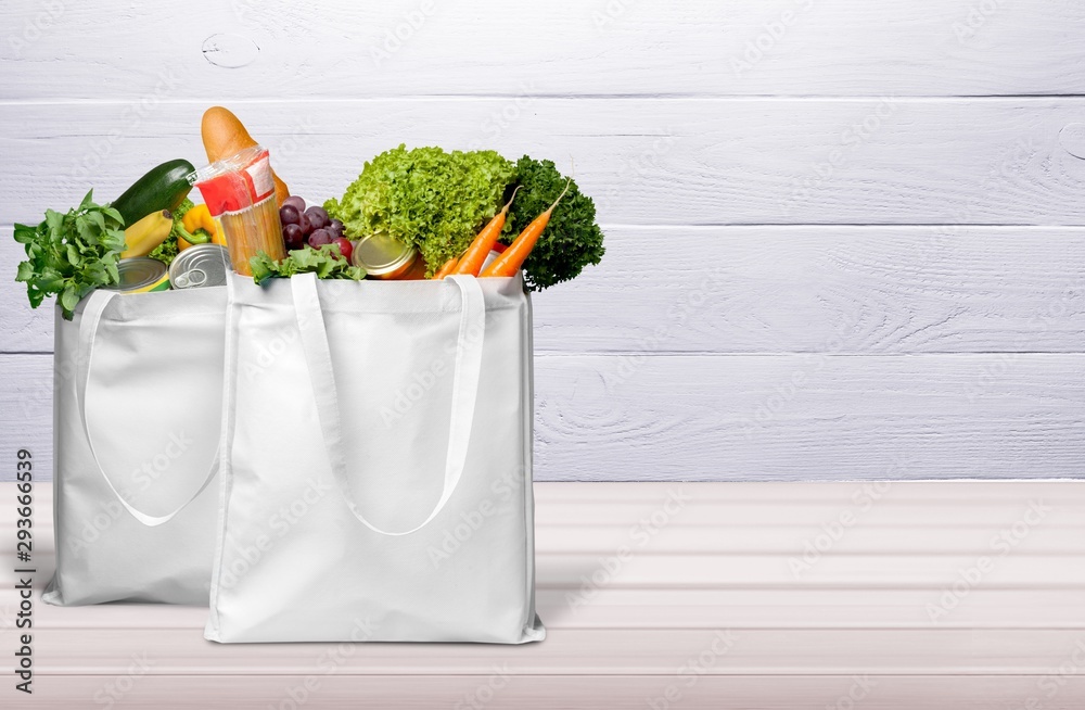 Bags with bread and variety vegetables on bright background