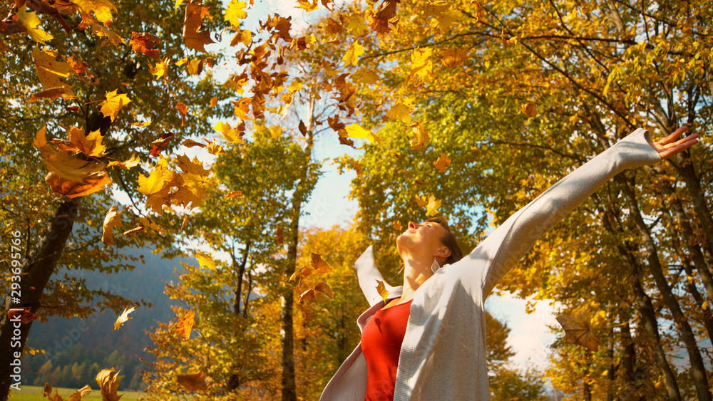 COPY SPACE: Girl spins with her arms outstretched as dry leaves fall on her.