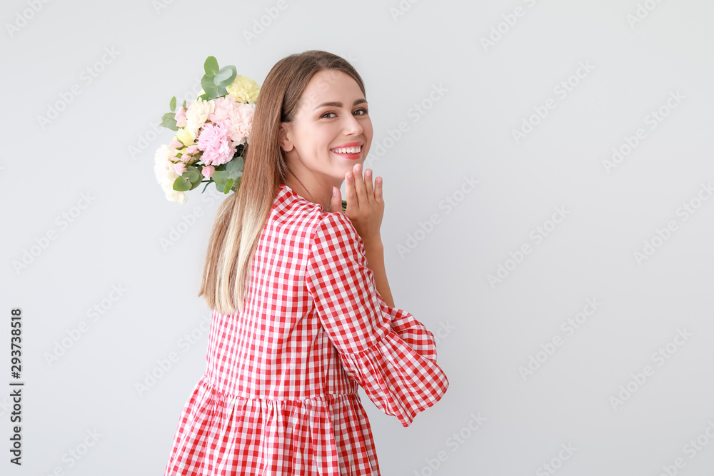 美丽的年轻女子，浅色背景上有一束康乃馨花