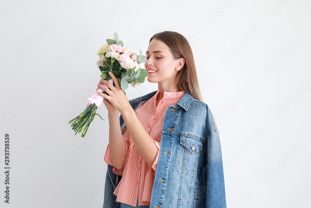 美丽的年轻女子，浅色背景上有一束康乃馨花