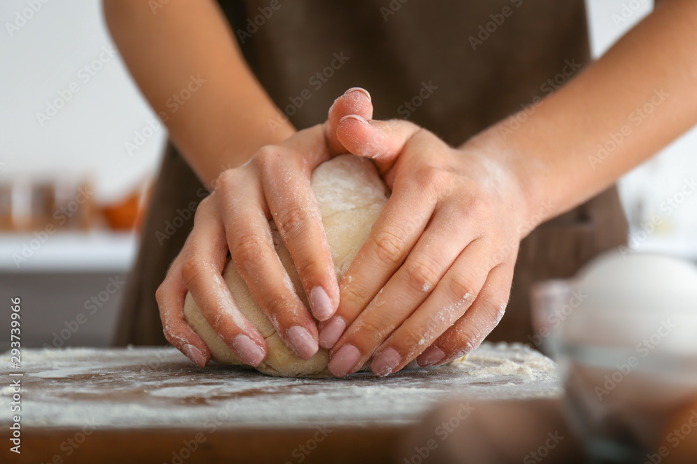 Woman kneading flour in kitchen, closeup