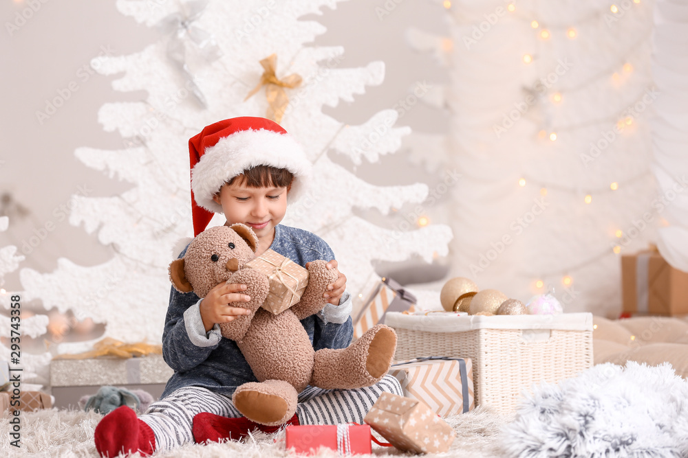 Cute little boy with teddy bear and Christmas gift at home