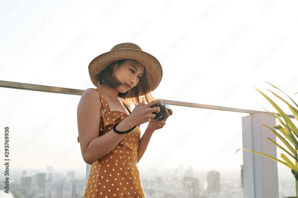 年轻漂亮的亚洲旅行女性使用数码相机和微笑