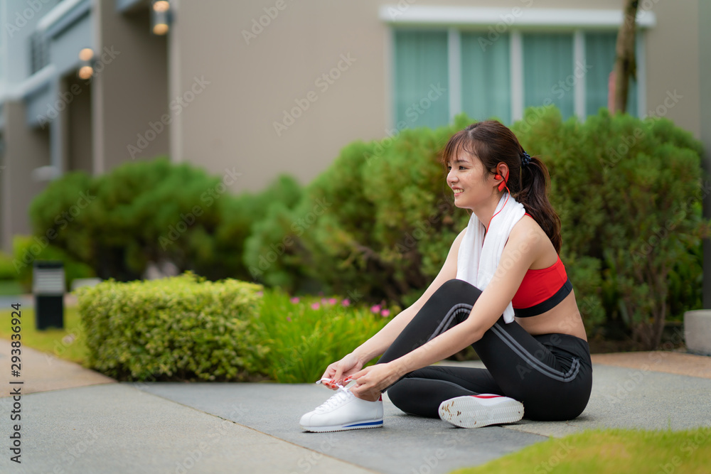 亚洲美女坐在村里的房子前放松，试鞋带，很开心