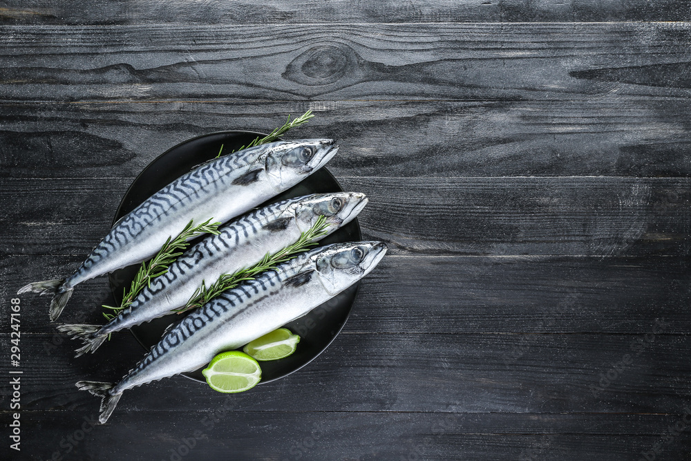 Plate with raw mackerel fish on dark table