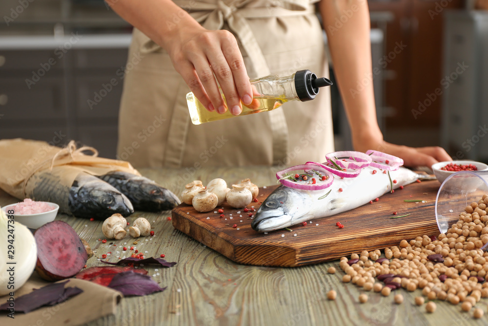 Woman preparing mackerel fish in kitchen, closeup