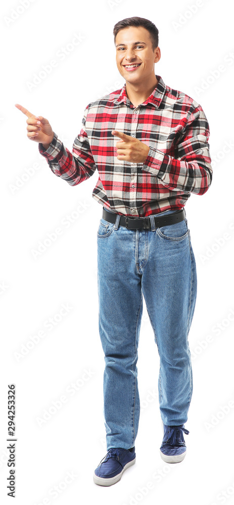 Portrait of handsome young man pointing at something on white background