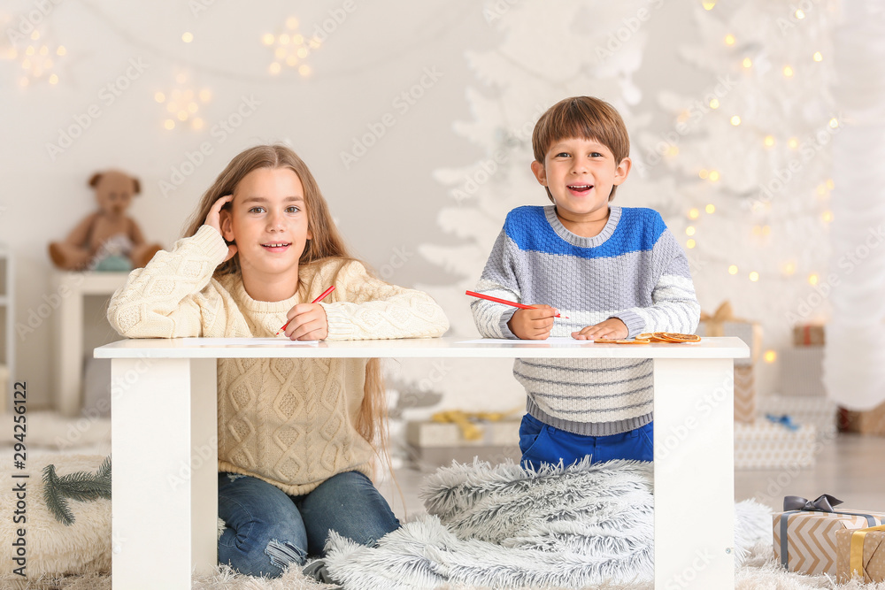 Little children writing letter to Santa Claus on Christmas eve at home