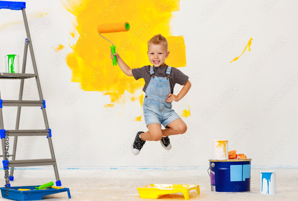 Repair in apartment. Happy child boy jumping paints wall