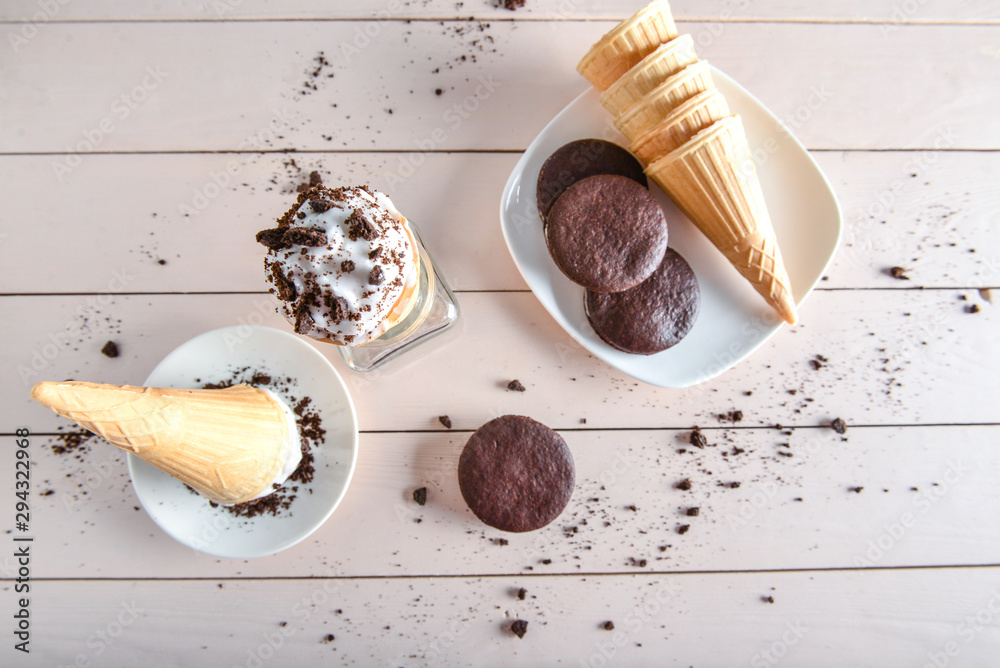 Wafer cones with tasty ice cream and chocolate cookies on table