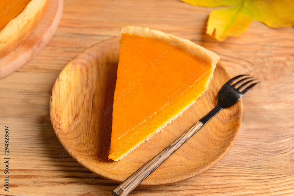 Plate with piece of tasty pumpkin pie on table