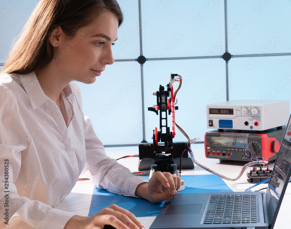 A young woman writes an algorithm for the robot arm. Science Research Laboratory for Robotic Arm Mod