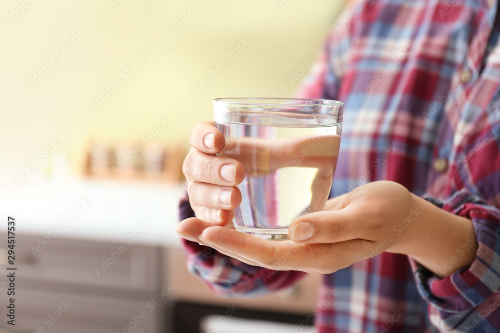 厨房里拿着一杯淡水的女人，特写