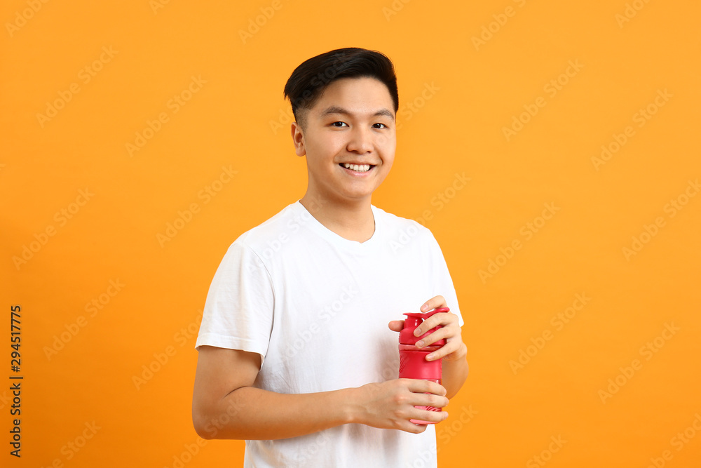 Portrait of Asian sportsman with bottle of water on color background