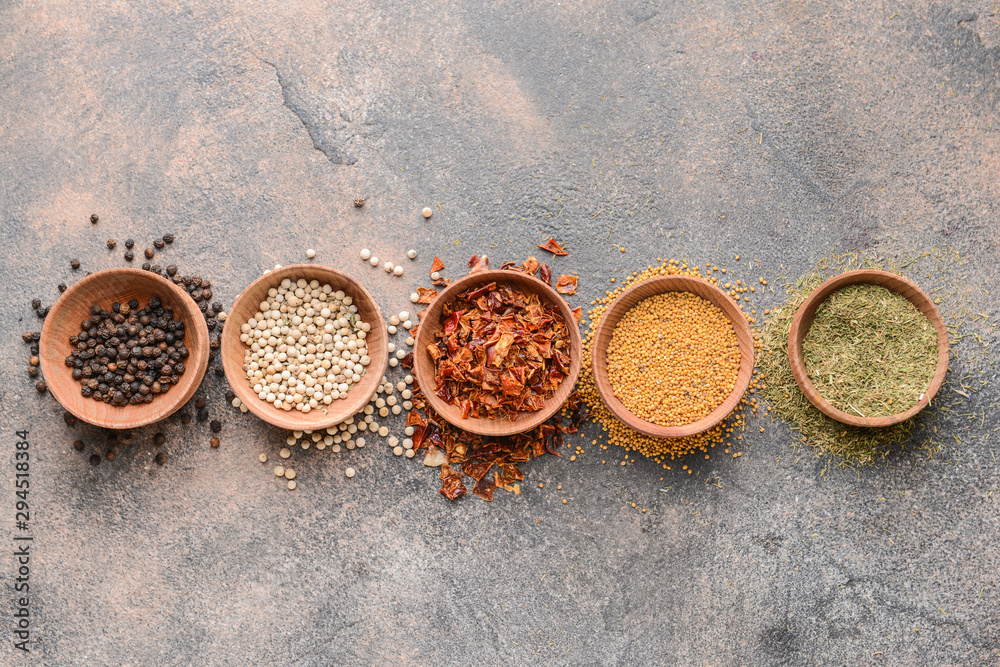 Bowls with different spices on grey background