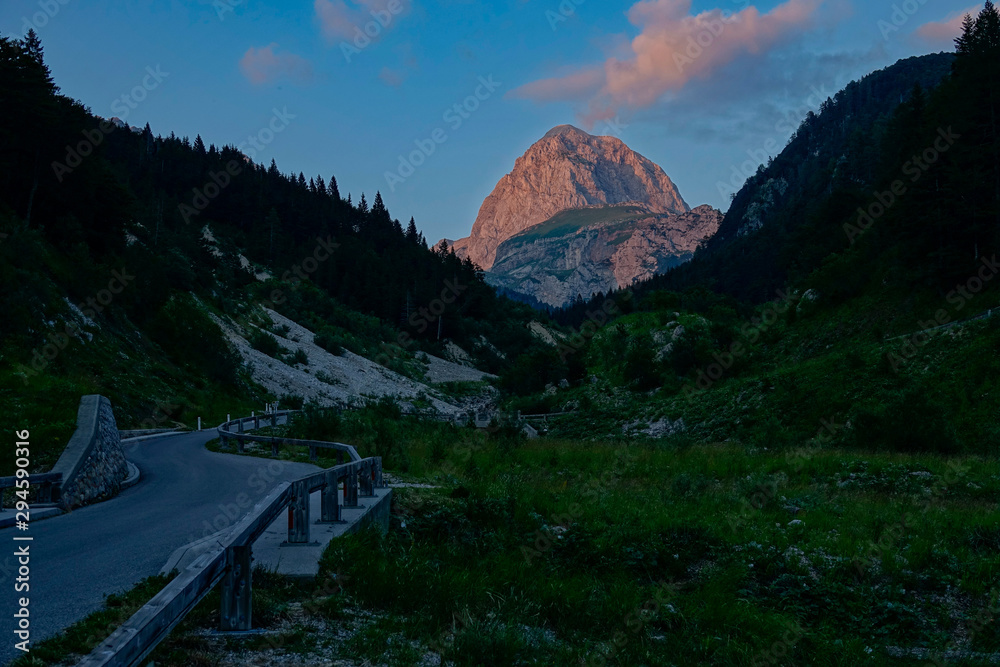 空旷的柏油路沿着山谷走向日落时的岩石山。